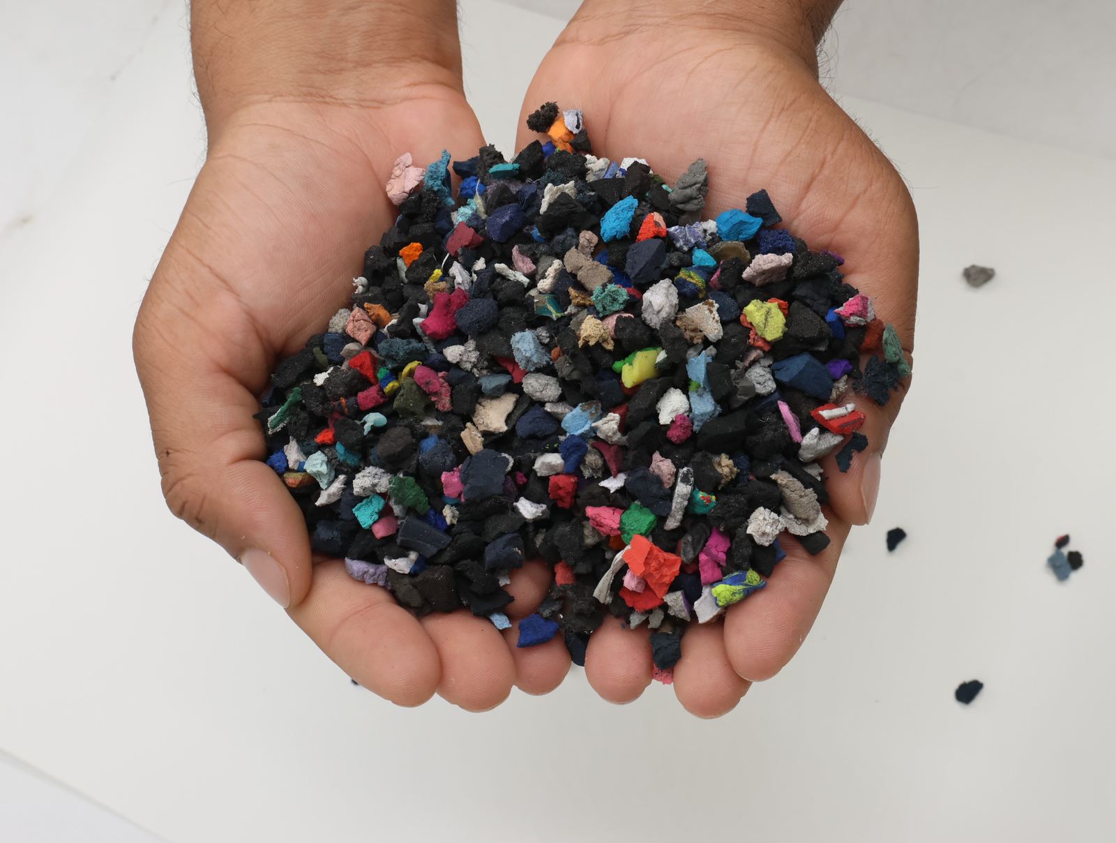 Hands holding mixed rubber and foam granulate